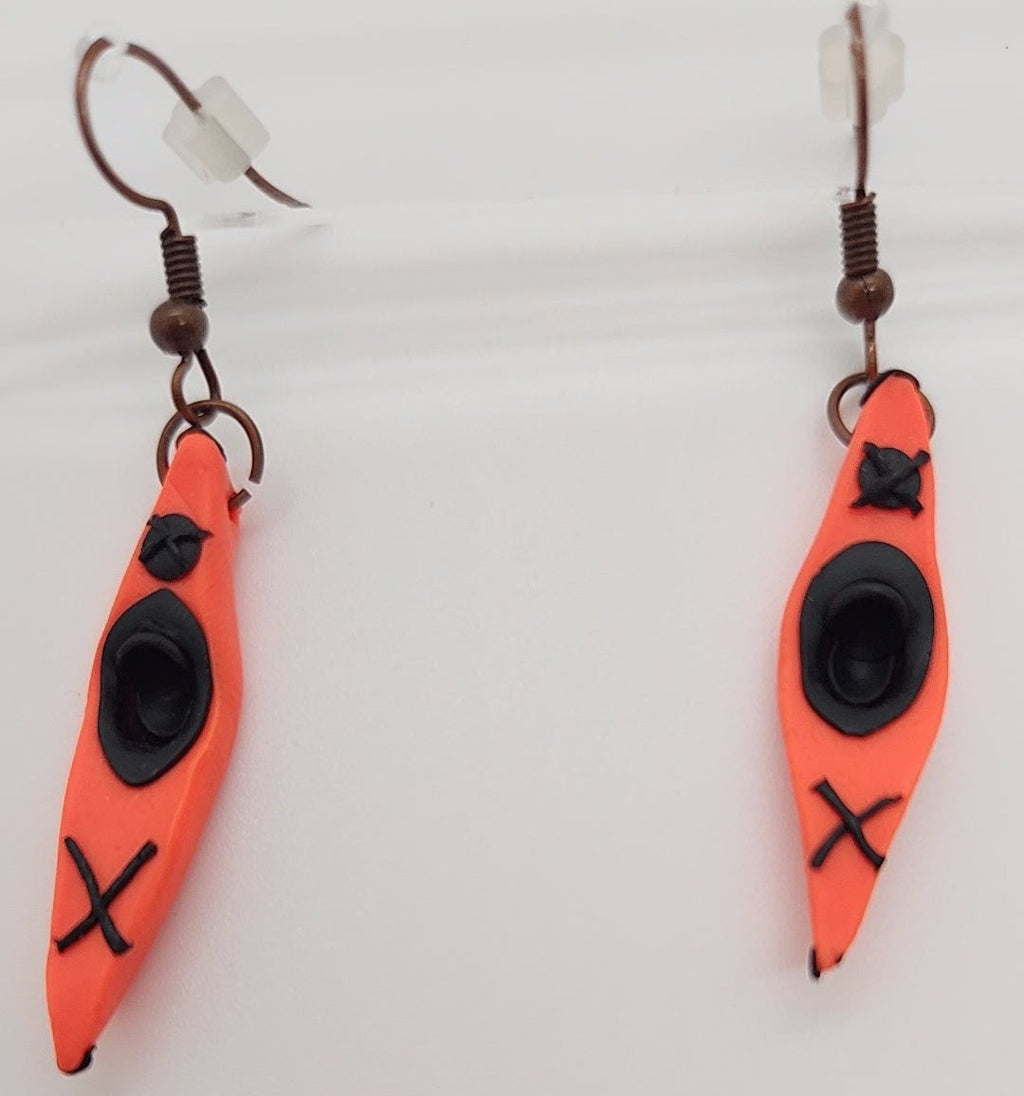 Orange kayak-shaped earrings with black X design on a white background